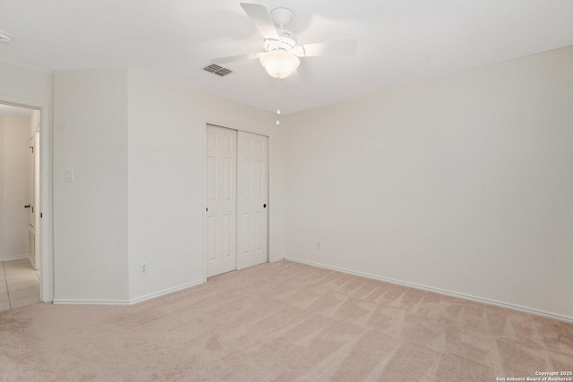 unfurnished bedroom with ceiling fan, light colored carpet, and a closet