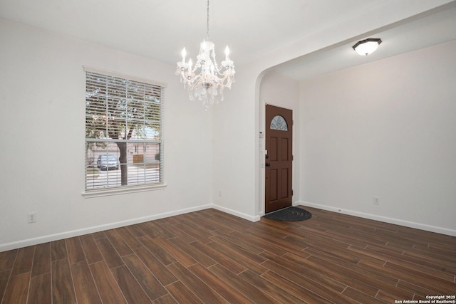 entryway with dark hardwood / wood-style floors and a notable chandelier