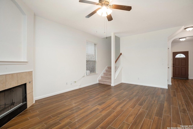 unfurnished living room with a tile fireplace, ceiling fan, and dark hardwood / wood-style flooring