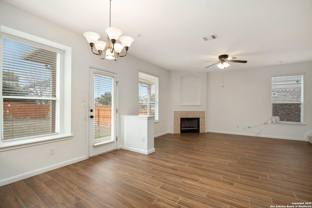 unfurnished living room featuring dark hardwood / wood-style flooring, ceiling fan with notable chandelier, and a tile fireplace