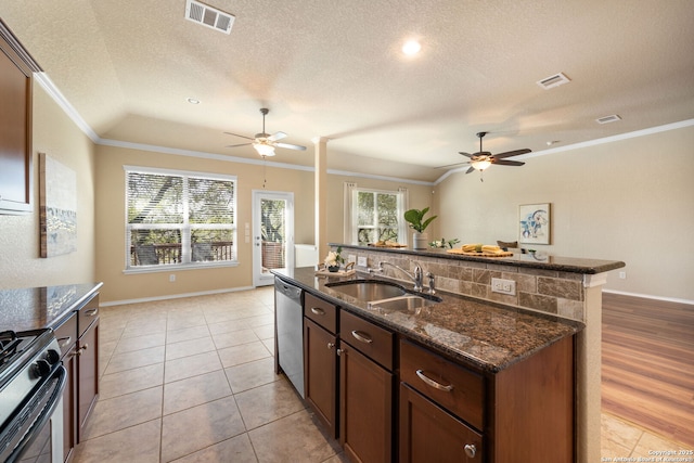 kitchen with sink, crown molding, stainless steel appliances, a center island with sink, and dark stone counters