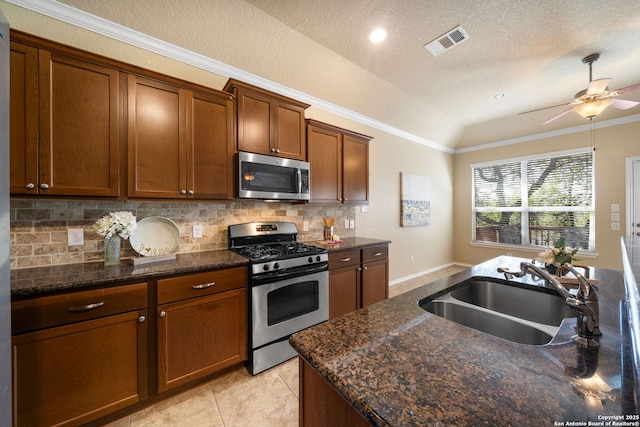 kitchen featuring backsplash, appliances with stainless steel finishes, sink, and dark stone counters