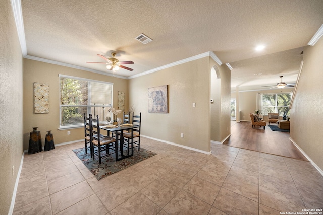 tiled dining room with crown molding, ceiling fan, and a textured ceiling