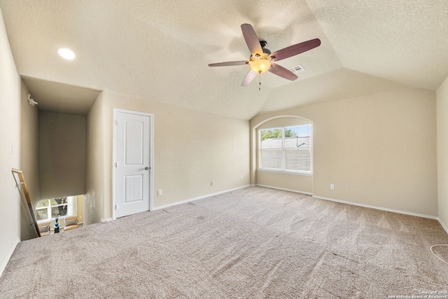 carpeted empty room featuring ceiling fan, lofted ceiling, and a textured ceiling