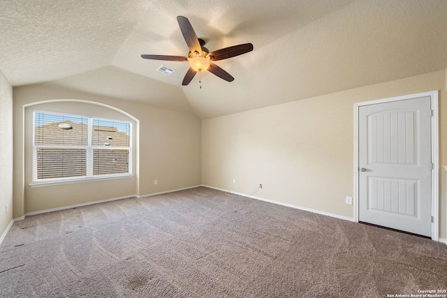 empty room featuring vaulted ceiling, carpet floors, ceiling fan, and a textured ceiling