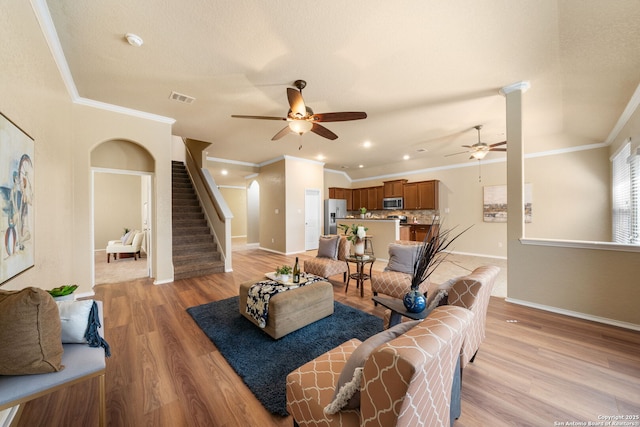 living room with crown molding, ceiling fan, and light wood-type flooring