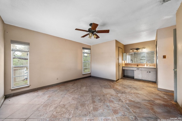 interior space featuring ceiling fan, sink, and a wealth of natural light