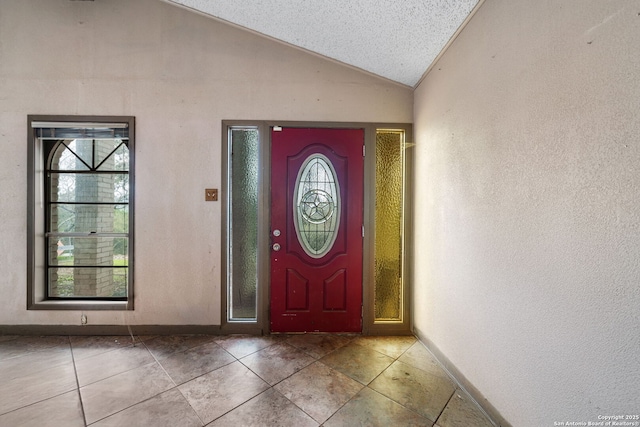 tiled foyer featuring lofted ceiling, a textured ceiling, and a healthy amount of sunlight