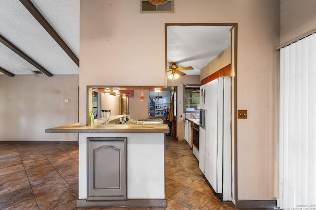 kitchen featuring a breakfast bar area, beam ceiling, white fridge with ice dispenser, a textured ceiling, and kitchen peninsula