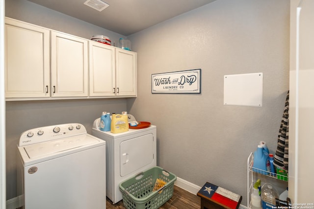 clothes washing area featuring dark hardwood / wood-style floors, washing machine and dryer, and cabinets