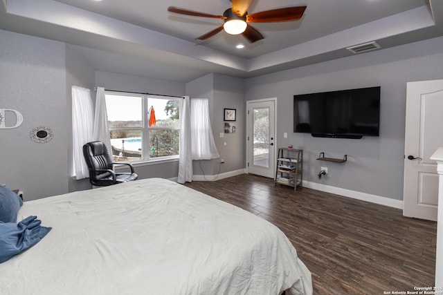 bedroom featuring ceiling fan, access to outside, dark hardwood / wood-style flooring, and a tray ceiling