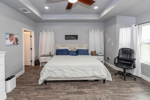 bedroom featuring a tray ceiling, dark hardwood / wood-style floors, and ceiling fan