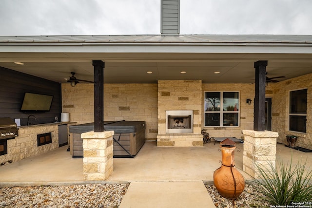 view of patio with an outdoor stone fireplace, a grill, ceiling fan, and an outdoor kitchen