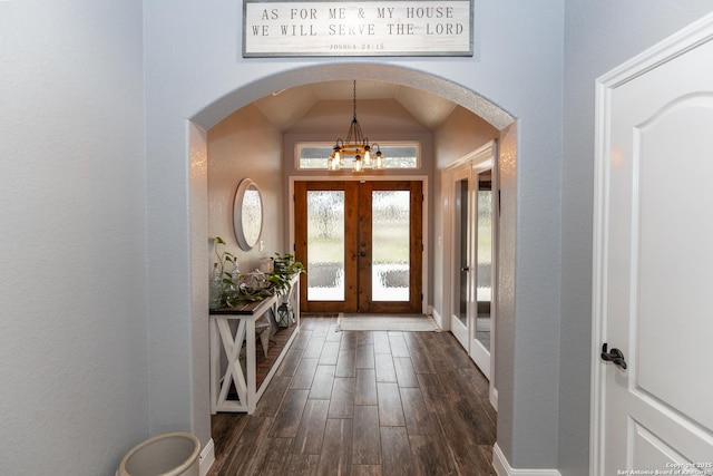 entrance foyer with an inviting chandelier, dark hardwood / wood-style floors, vaulted ceiling, and french doors