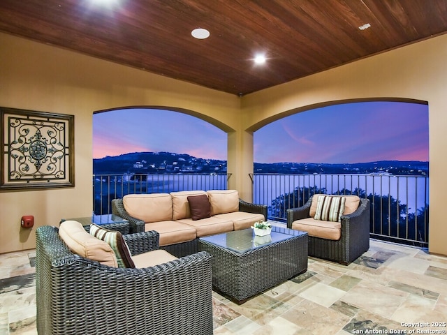 patio terrace at dusk with an outdoor hangout area and a water view