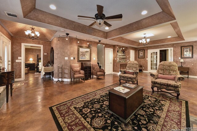 living room with a tray ceiling and ceiling fan with notable chandelier