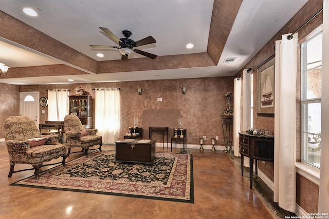 living room featuring ceiling fan, a healthy amount of sunlight, and a raised ceiling