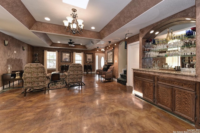 bar featuring sink, ceiling fan, and a tray ceiling