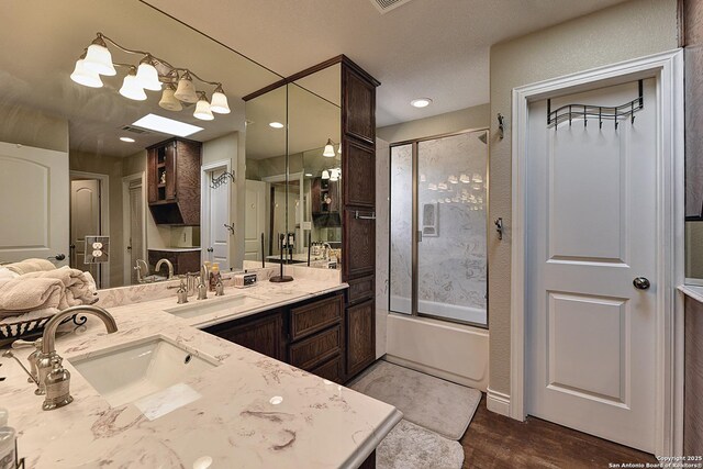 bathroom featuring hardwood / wood-style flooring, enclosed tub / shower combo, and vanity