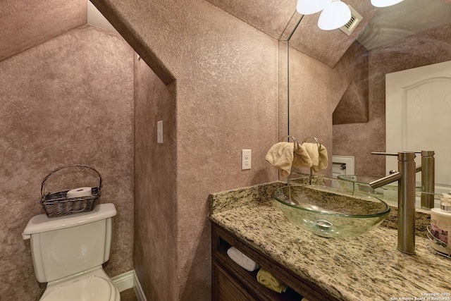 bathroom with vanity, vaulted ceiling, and toilet