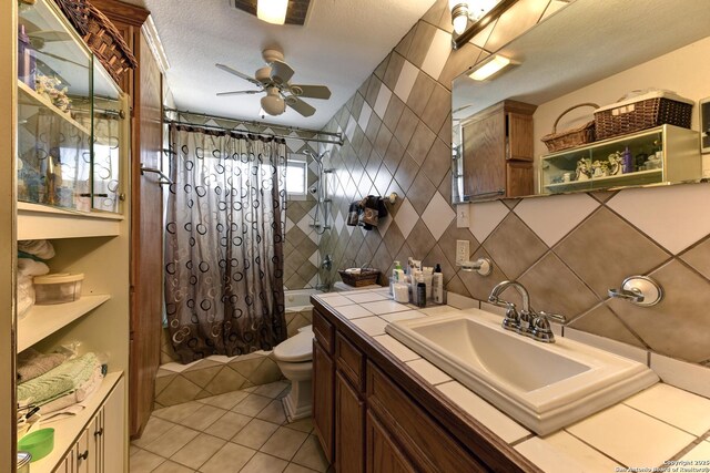 full bathroom featuring shower / tub combo with curtain, tile walls, vanity, ceiling fan, and toilet