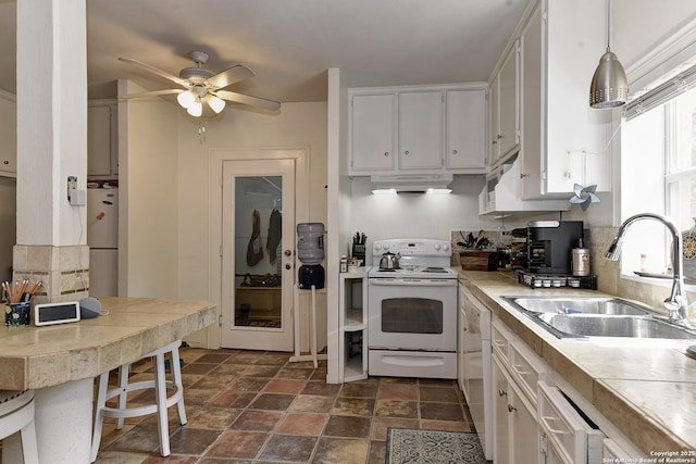 kitchen featuring white cabinetry, sink, pendant lighting, and white appliances