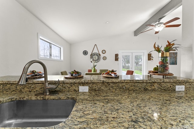 kitchen with stone countertops, sink, vaulted ceiling with beams, ceiling fan, and french doors