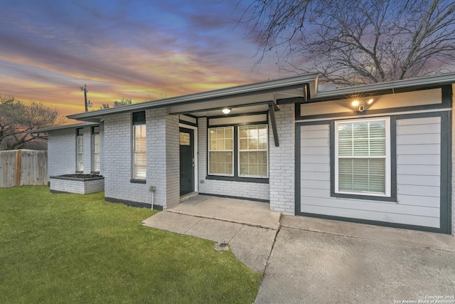 back house at dusk with a patio and a yard