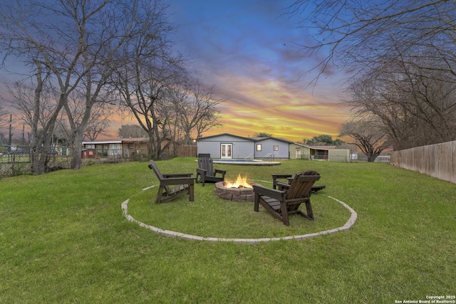 yard at dusk featuring an outdoor structure and an outdoor fire pit