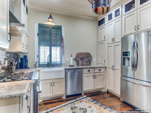 kitchen with wall chimney exhaust hood, ornamental molding, appliances with stainless steel finishes, light stone countertops, and decorative backsplash