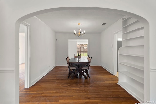 dining area with built in features, dark hardwood / wood-style floors, a notable chandelier, and crown molding