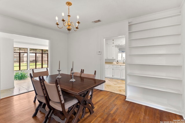 dining area featuring dark wood-type flooring, sink, and an inviting chandelier