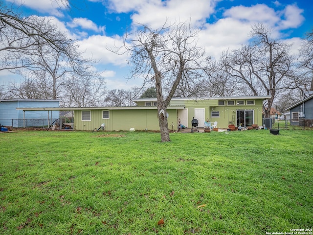 rear view of house featuring central AC unit and a lawn