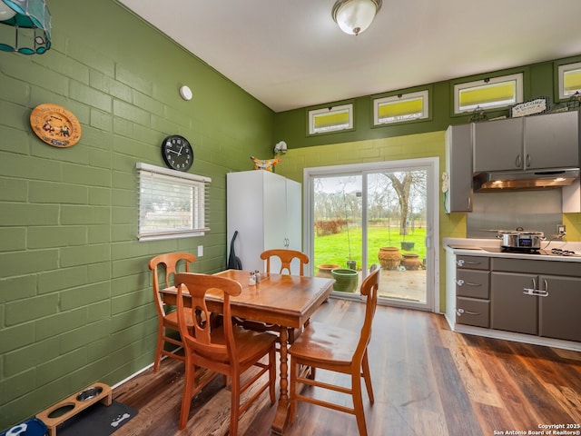 dining space with brick wall and dark hardwood / wood-style flooring