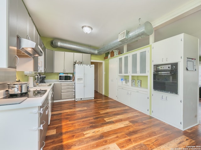 kitchen featuring dark wood-type flooring, exhaust hood, white cabinets, and black appliances