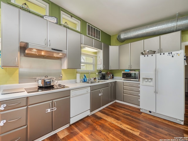 kitchen with white appliances, dark hardwood / wood-style flooring, sink, and decorative backsplash