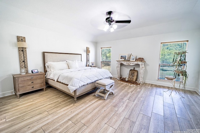 bedroom with multiple windows, light hardwood / wood-style floors, and ceiling fan