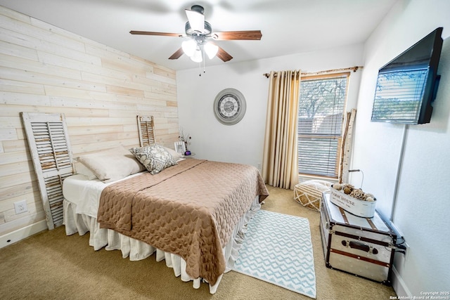 bedroom with ceiling fan, light carpet, and wood walls