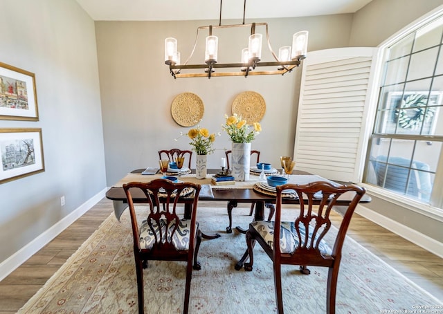 dining area featuring wood-type flooring and a notable chandelier