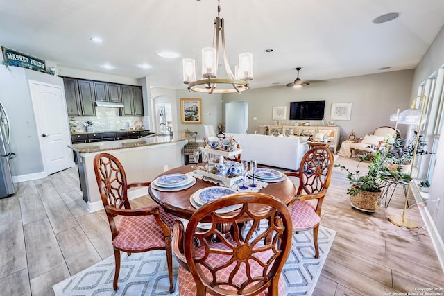 dining room with sink and ceiling fan with notable chandelier