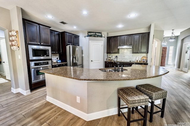 kitchen featuring appliances with stainless steel finishes, a kitchen island with sink, and light hardwood / wood-style floors