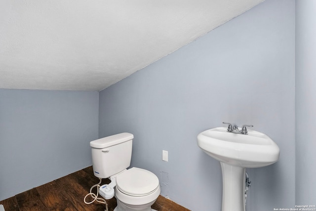 bathroom featuring a textured ceiling, wood-type flooring, toilet, and vaulted ceiling