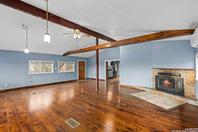 unfurnished living room featuring lofted ceiling with beams, a stone fireplace, hardwood / wood-style floors, and ceiling fan