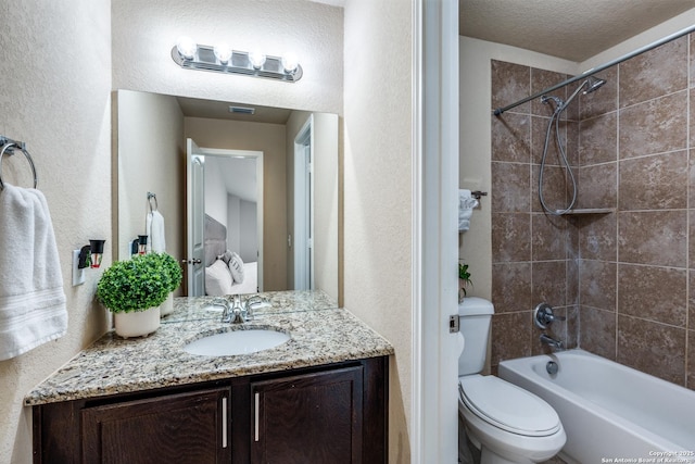 full bathroom with vanity, toilet, tiled shower / bath combo, and a textured ceiling