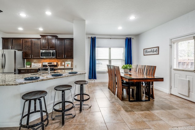 kitchen featuring light stone counters, backsplash, plenty of natural light, and appliances with stainless steel finishes