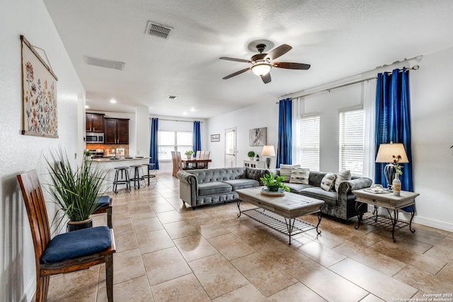 tiled living room with ceiling fan and a textured ceiling