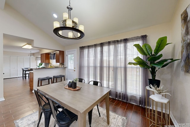 dining area with vaulted ceiling and an inviting chandelier