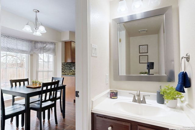 bathroom featuring vanity, backsplash, and an inviting chandelier