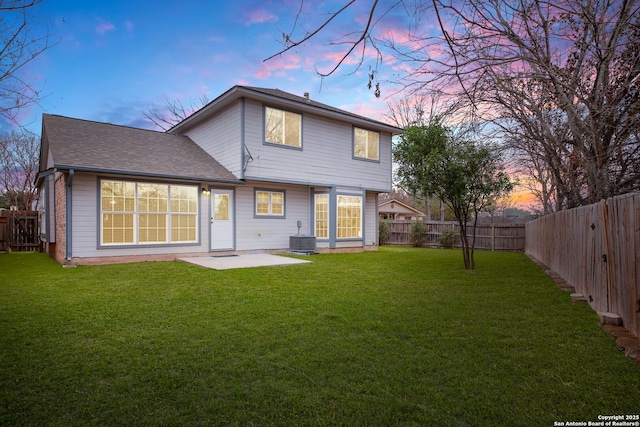 back house at dusk featuring a yard and a patio area