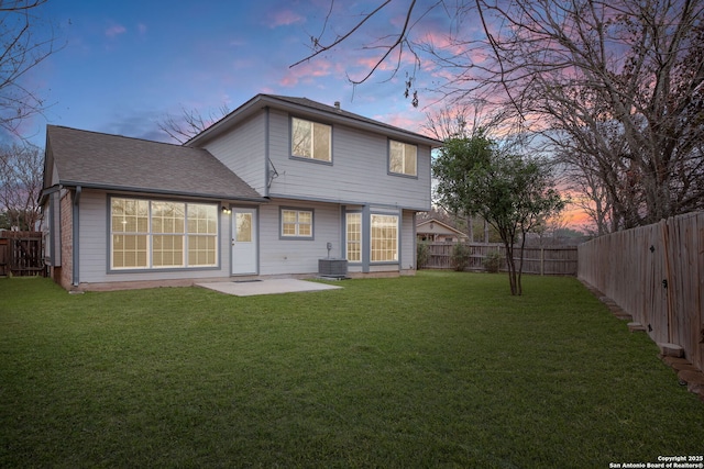 back house at dusk with a yard and a patio area